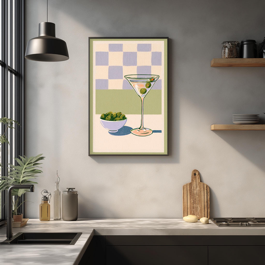 a kitchen counter with various items, including a framed illustration of a martini glass, a bowl of olives, and a wooden cutting board.