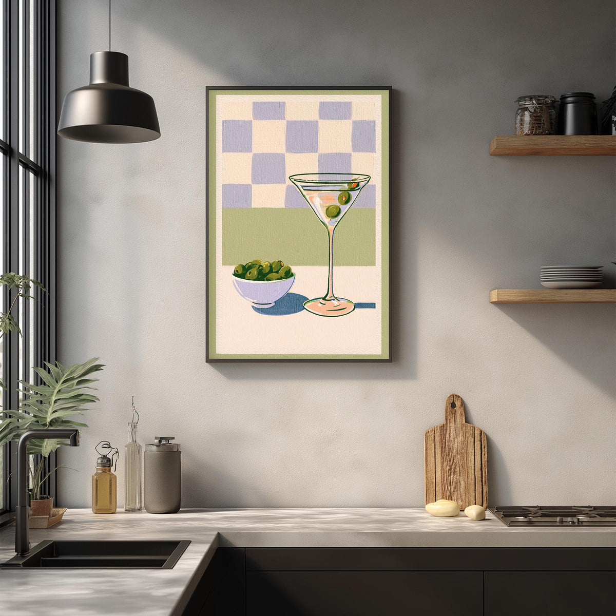 a kitchen counter with various items, including a framed illustration of a martini glass, a bowl of olives, and a wooden cutting board.