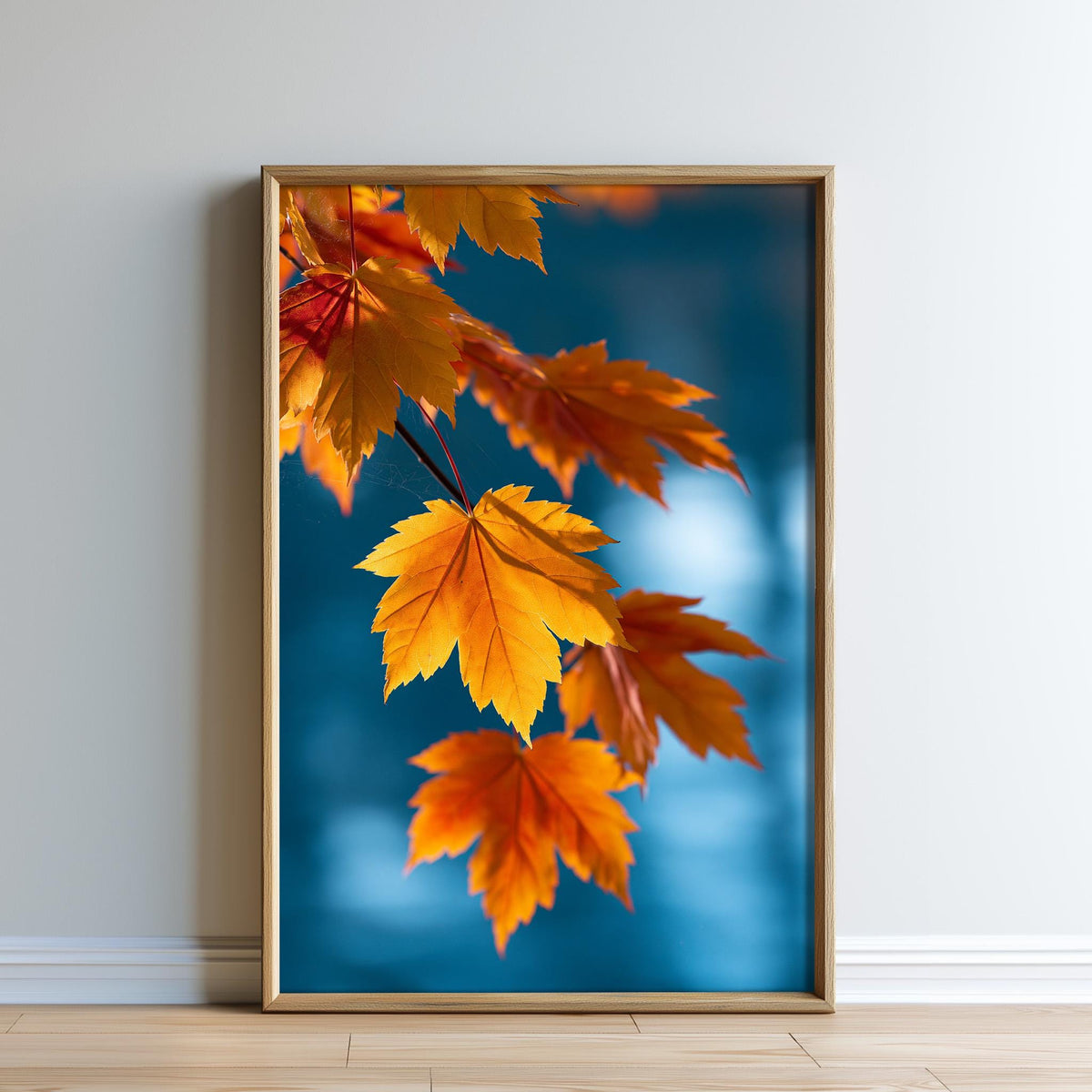 A framed photograph of vibrant orange and yellow autumn leaves against a blue background.