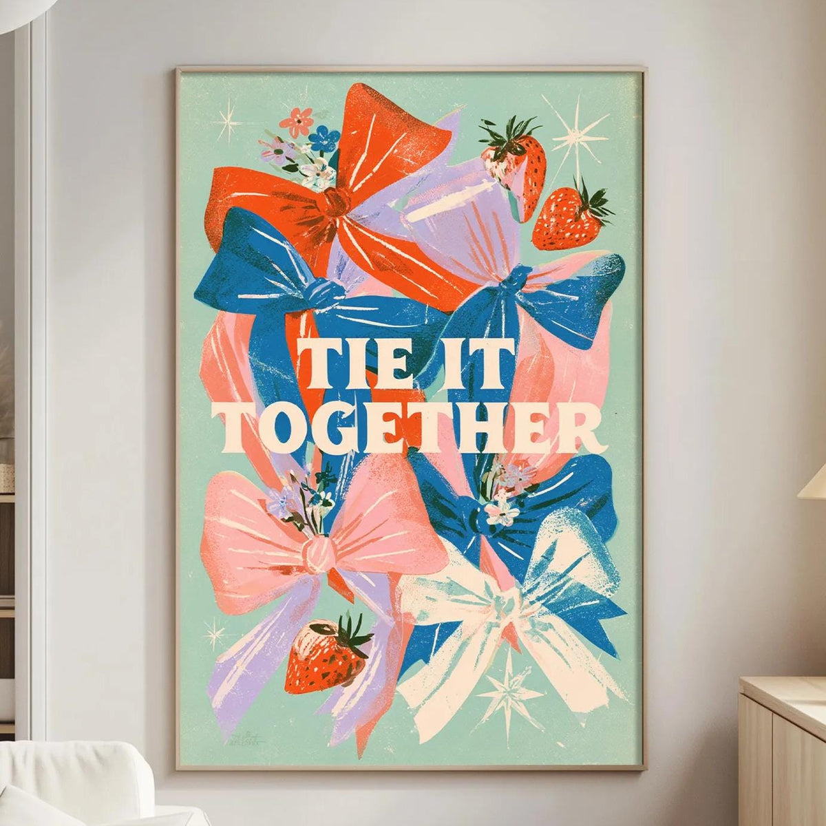 a living room with a large framed poster on the wall that says "tie it together" surrounded by colorful flowers and a star.