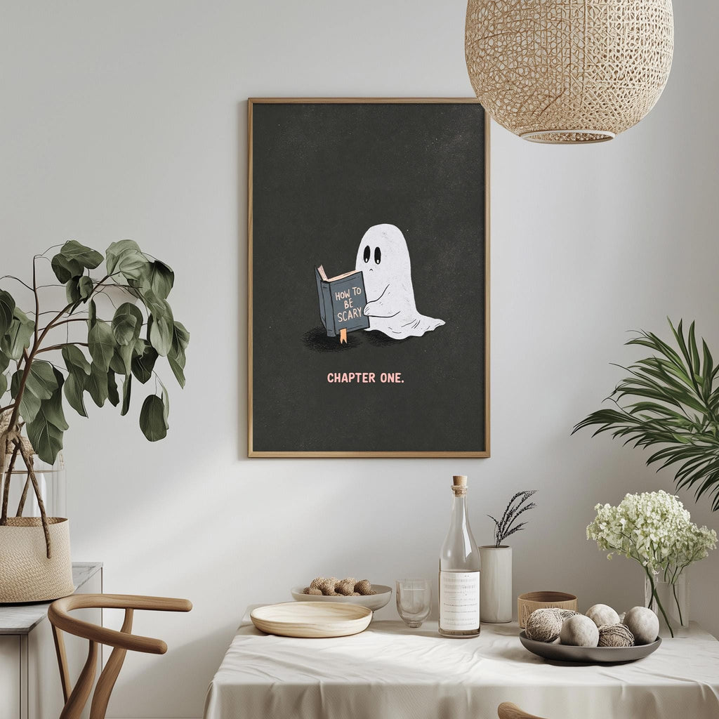 a framed poster of a ghost reading a book, with the text "How to scare someone" and "CHAPTER ONE." The poster is displayed on a wall above a table with various items on it, including a bottle, a bowl, and a vase.