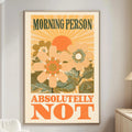 a poster with a floral design and the text "MORNING PERSON ABSOLUTELY NOT" displayed on a wall in a living room setting.