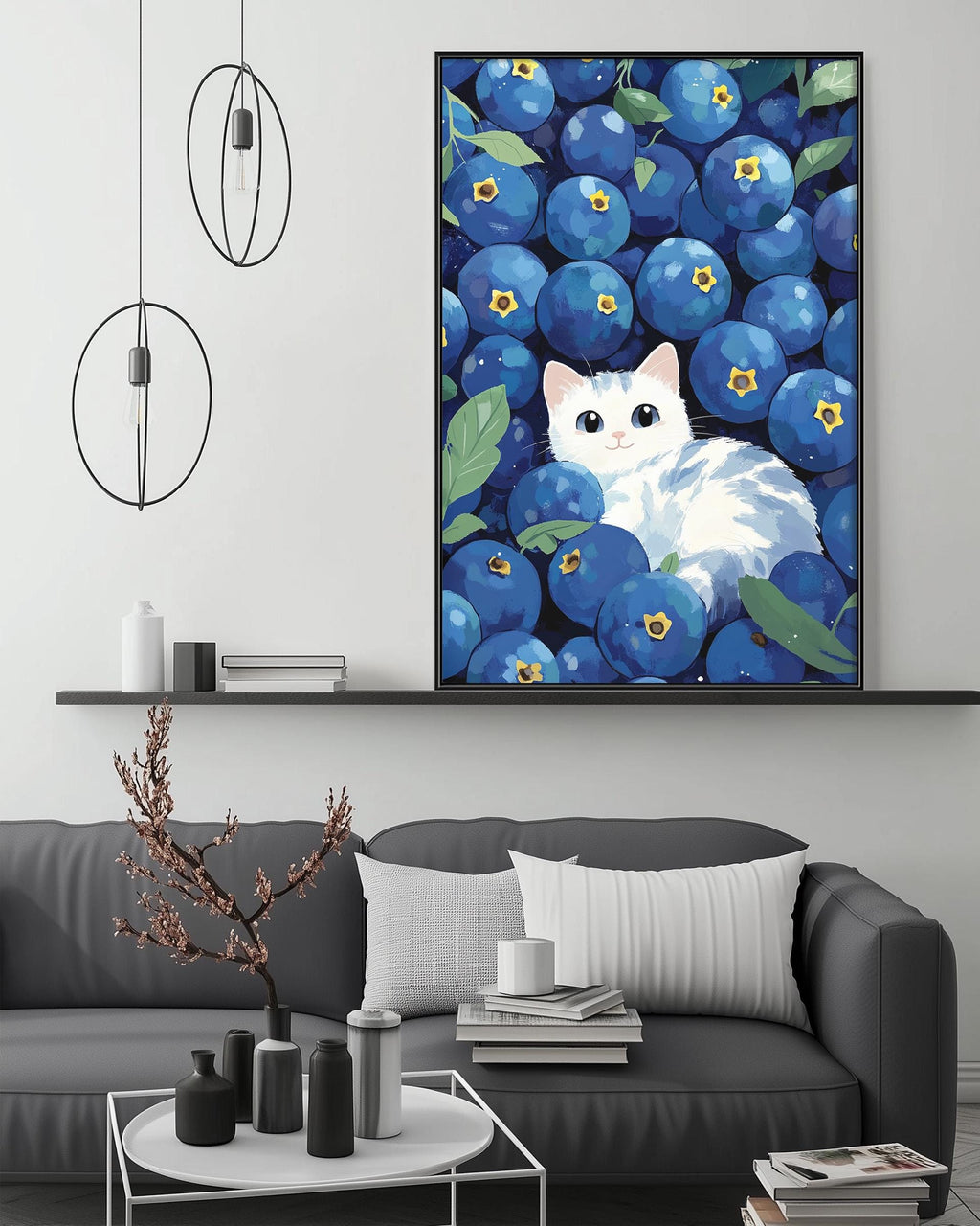 a large painting of a white cat surrounded by blueberries, hanging on a wall above a gray couch with a coffee table in front of it.