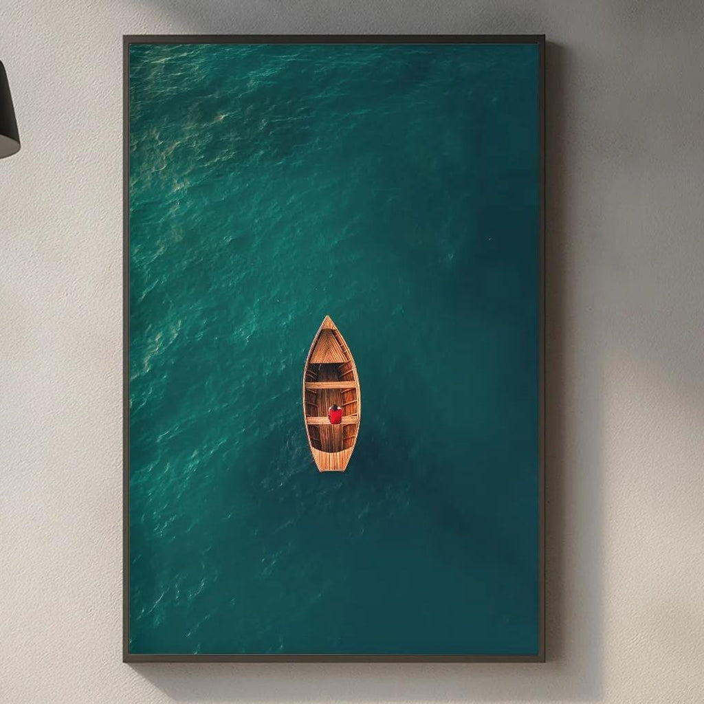 a kitchen counter with various kitchen items, including a cutting board, a bottle, and a vase. Above the counter, there is a framed picture of a boat floating on a turquoise body of water.