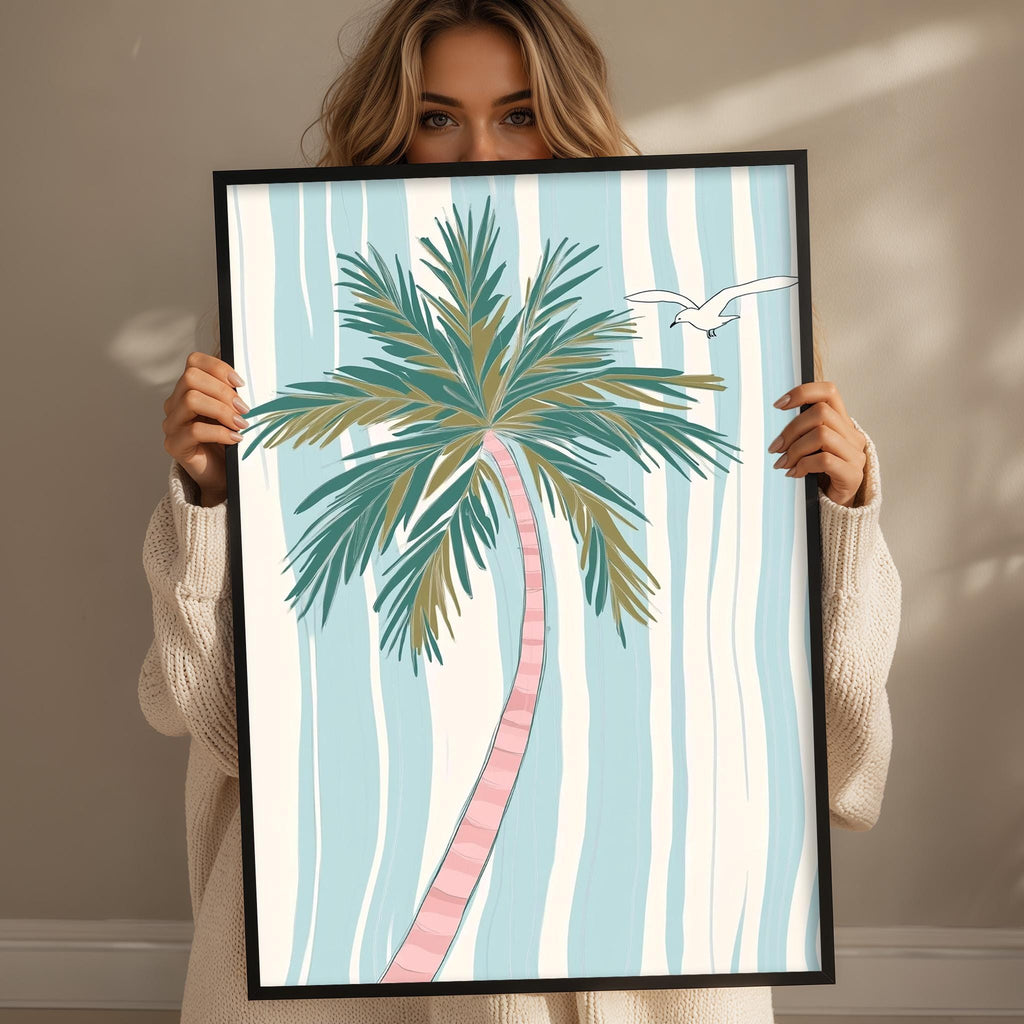 A woman holding a framed picture of a palm tree with a bird in the background.