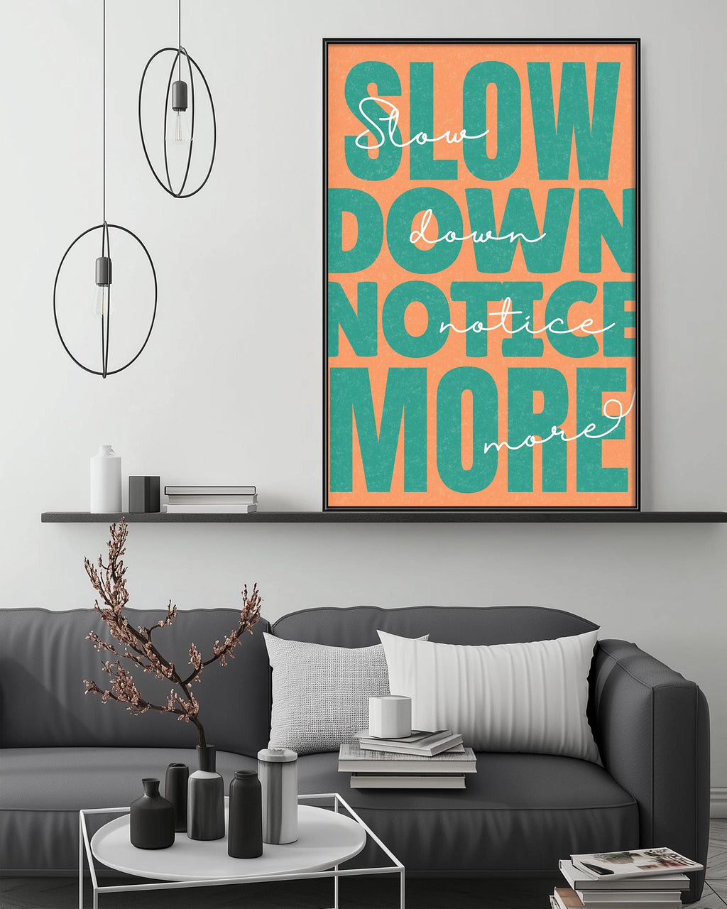 a modern living room with a gray sofa, a coffee table, and a large framed poster with the text "Slow down notice more" displayed on the wall above the sofa.