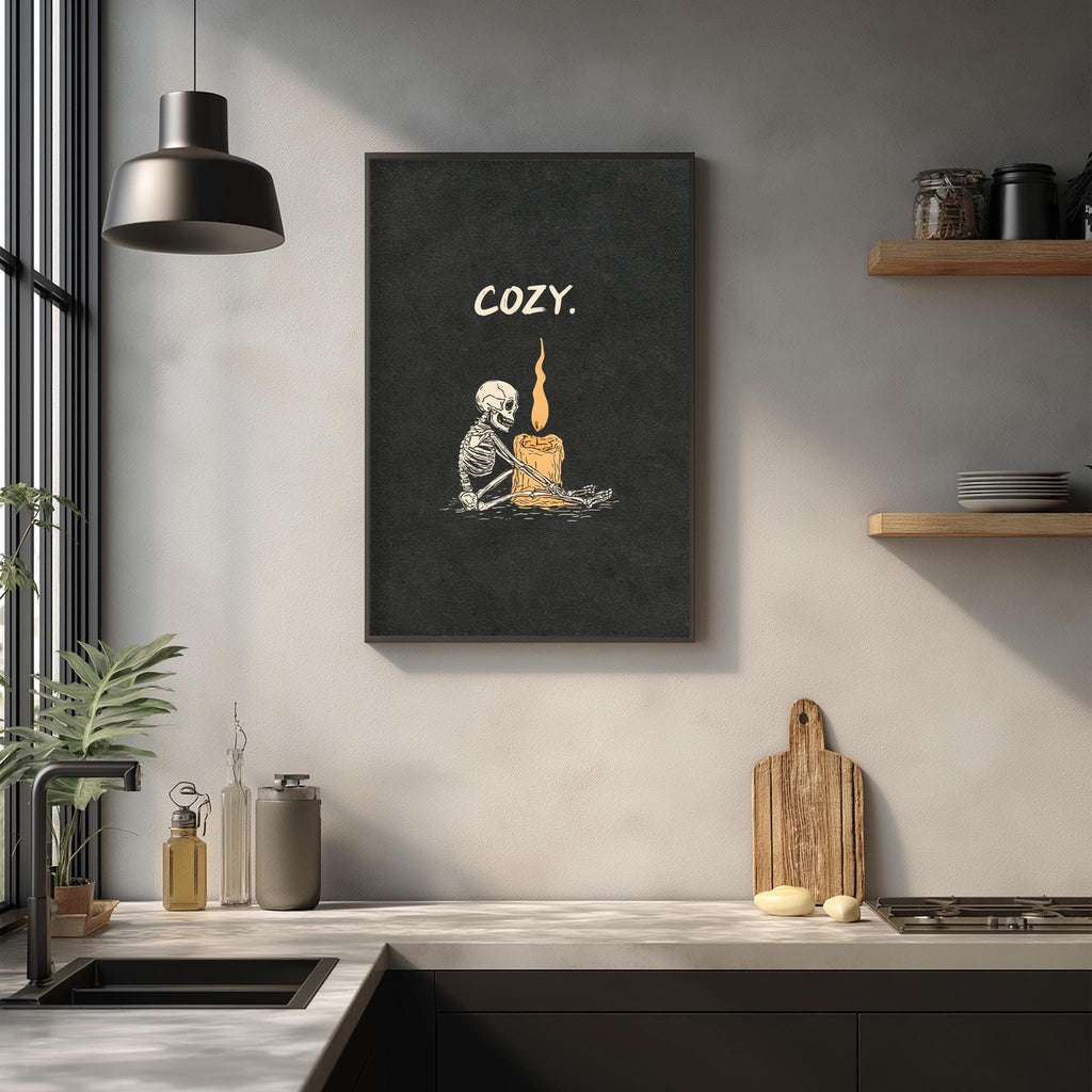 a kitchen counter with various items such as a wooden cutting board, a bottle, and a vase. Above the counter, there is a framed poster with an illustration of a skeleton holding a lit candle, accompanied by the word "COZY".