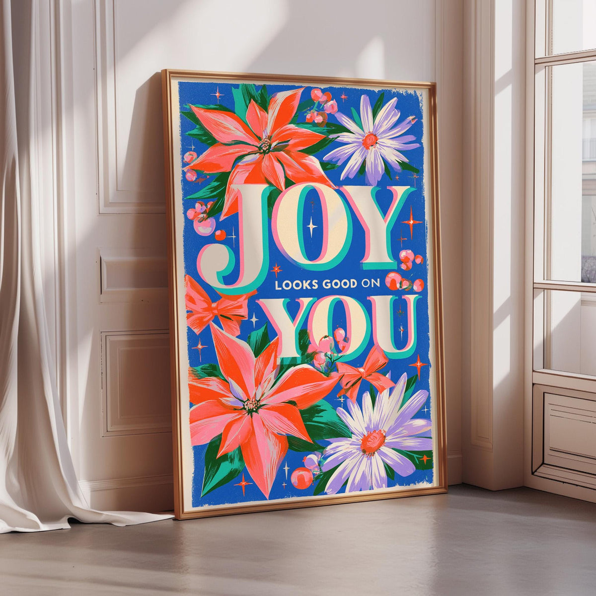 A framed poster with a vibrant floral design and the text "JOY YOU LOOKS GOOD ON YOU" displayed on it.
