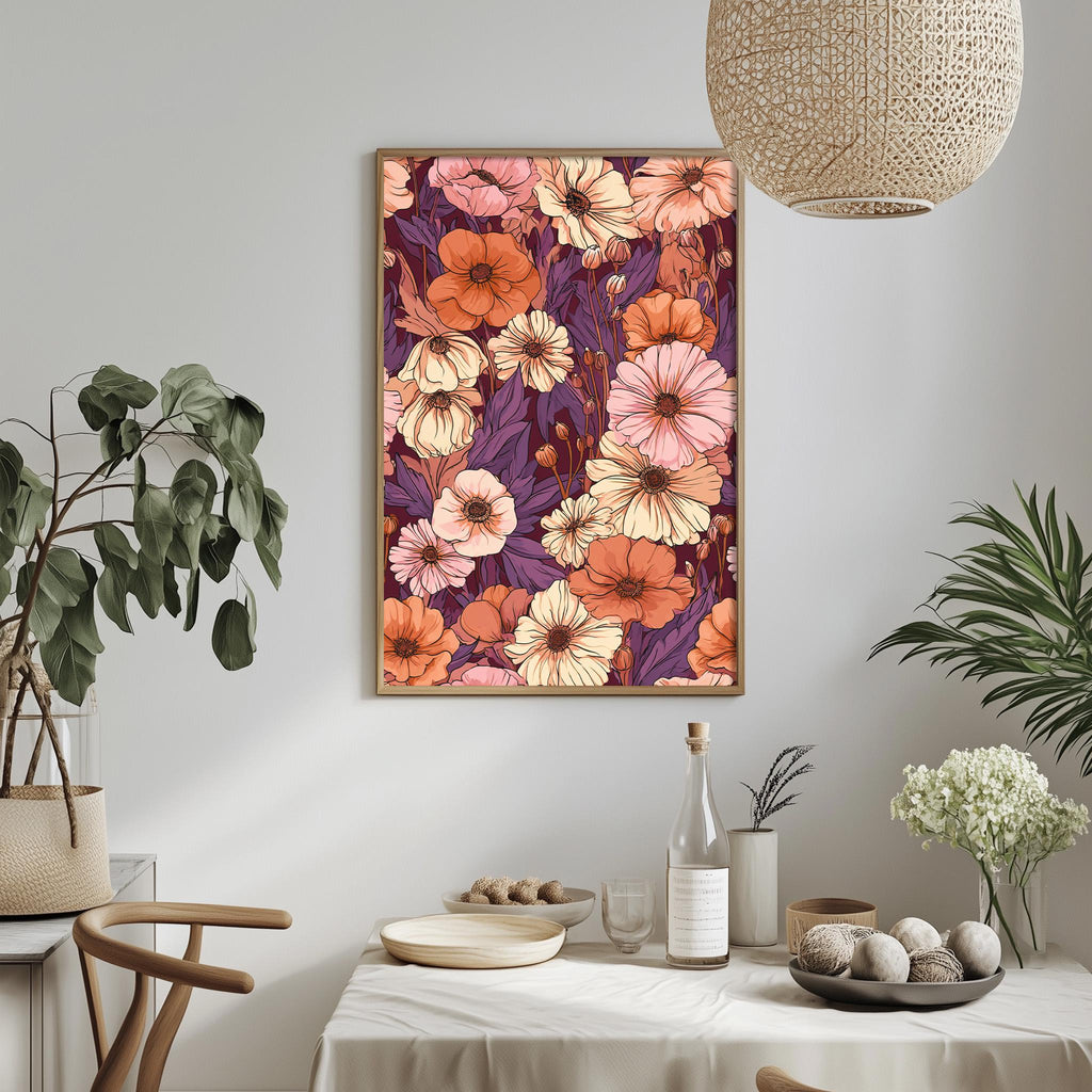 a dining table with a white tablecloth, a bowl of fruit, a bottle, and a vase with flowers. Above the table, there is a framed picture of a floral pattern in shades of pink, orange, and purple. The table is set with a plate, a cup, and a bowl. The room has a minimalist and modern design, with a woven light fixture hanging above the table and potted plants adding a touch of greenery.