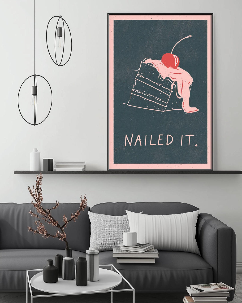 a modern living room with a gray sofa, a coffee table, and a framed poster on the wall. The poster depicts a slice of cake with a cherry on top, accompanied by the text "Nailed it."