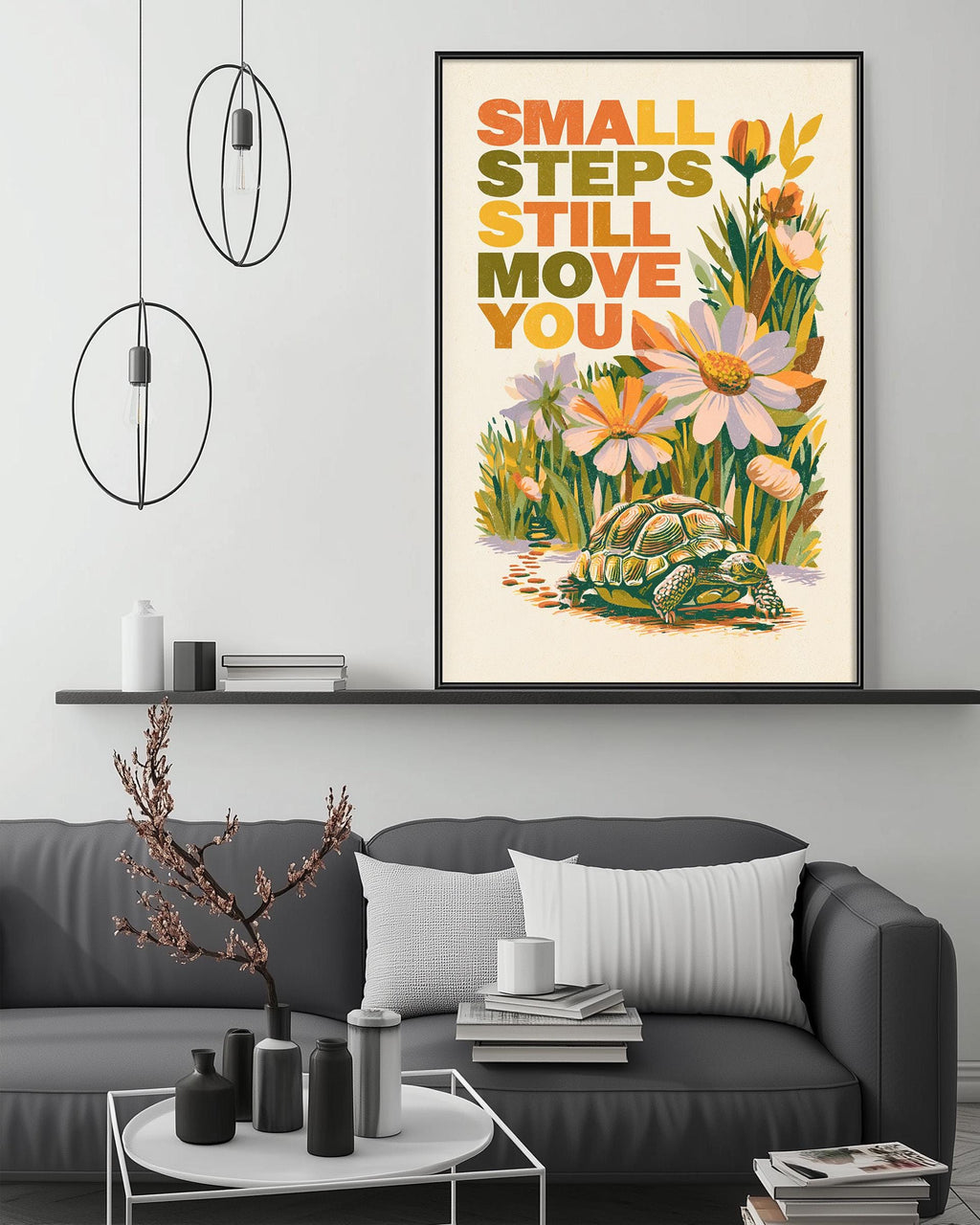 a framed poster with the text "Small steps still move you" and an illustration of a turtle surrounded by flowers. The poster is displayed above a gray couch in a living room setting, with a coffee table and decorative items in the foreground.
