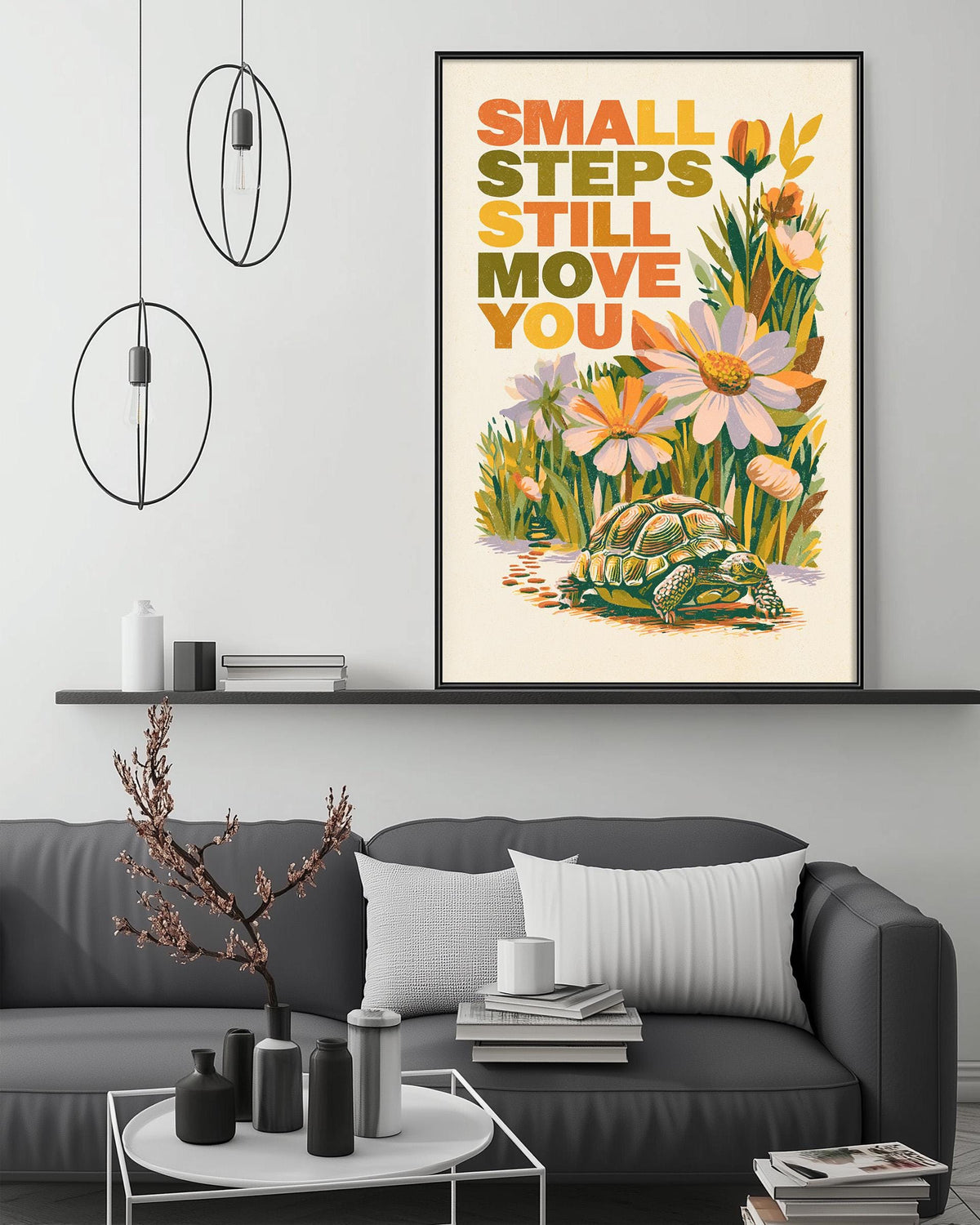 a framed poster with the text "Small steps still move you" and an illustration of a turtle surrounded by flowers. The poster is displayed above a gray couch in a living room setting, with a coffee table and decorative items in the foreground.