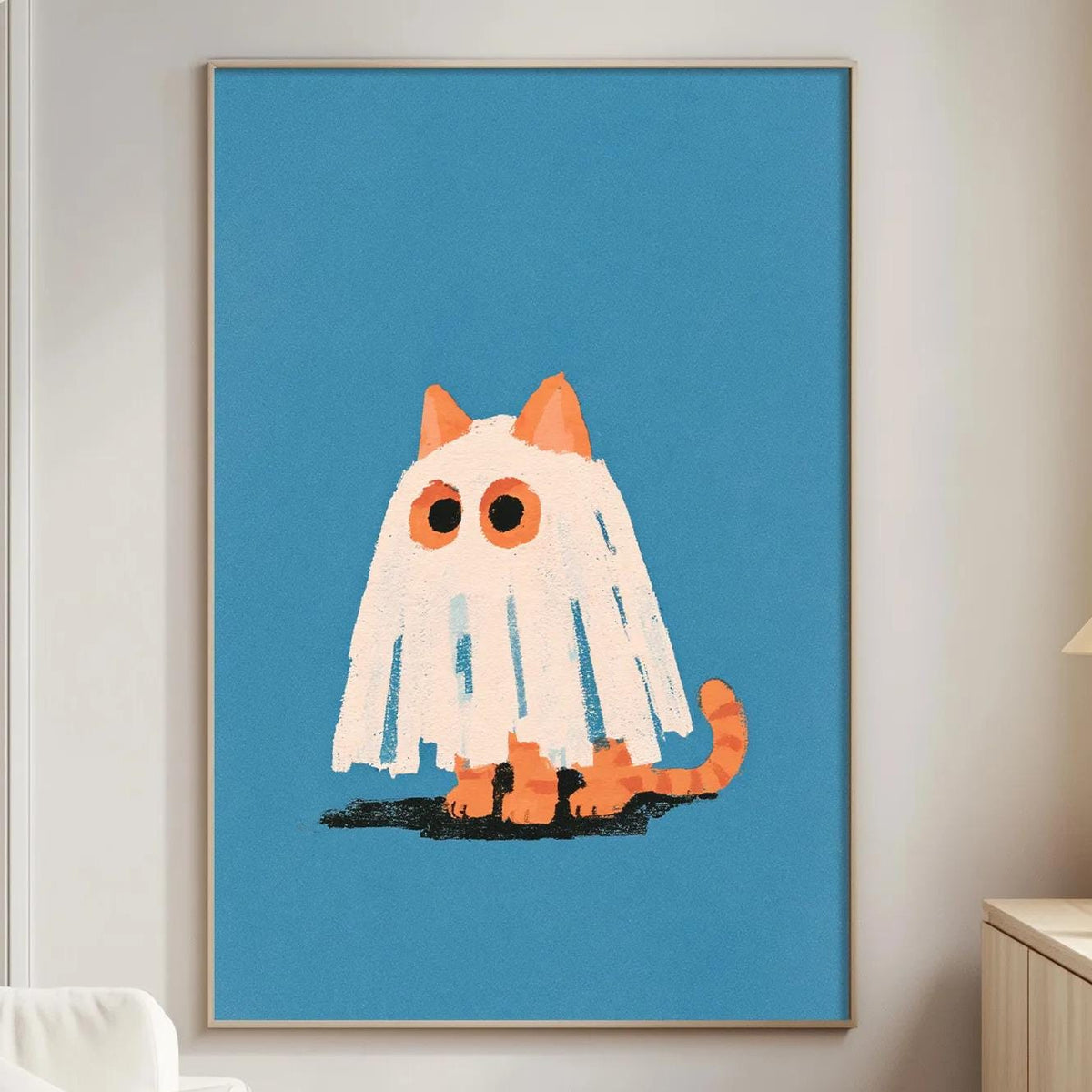 a cozy living room with a white couch, a wooden side table, and a framed poster of a ghost cat on the wall.
