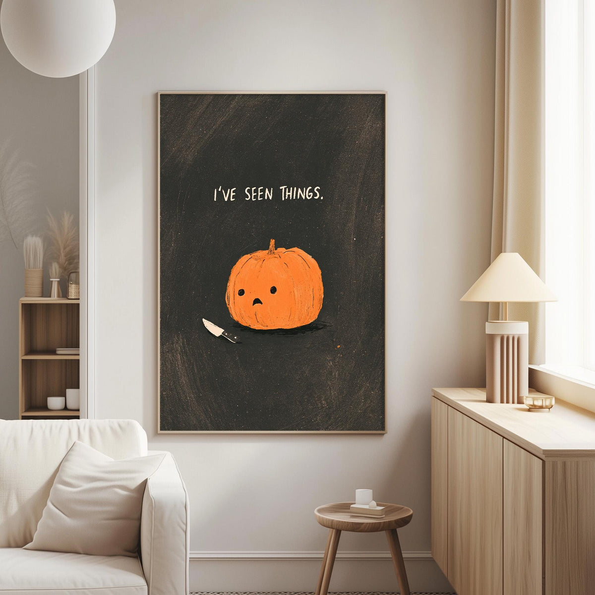 a living room with a white couch, a wooden side table, and a lamp. The wall has a framed illustration of a pumpkin with the text "I've seen things" above it.