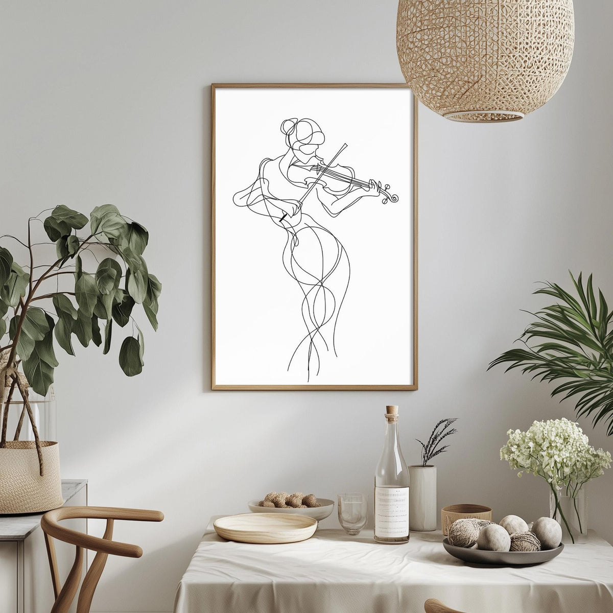 a minimalist dining room with a framed drawing of a woman playing a violin hanging on the wall. The dining table is set with various items, including a bottle, a bowl, and a vase with flowers. The room is decorated with potted plants and a woven light fixture, creating a serene and elegant atmosphere.