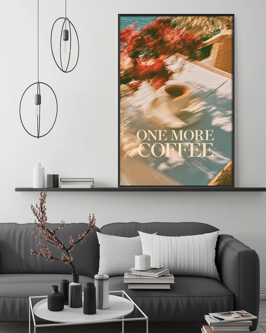 a cozy living room with a gray sofa, a coffee table, and a large framed poster of a coffee cup with the text "ONE MORE COFFEE" displayed on the wall above the sofa.