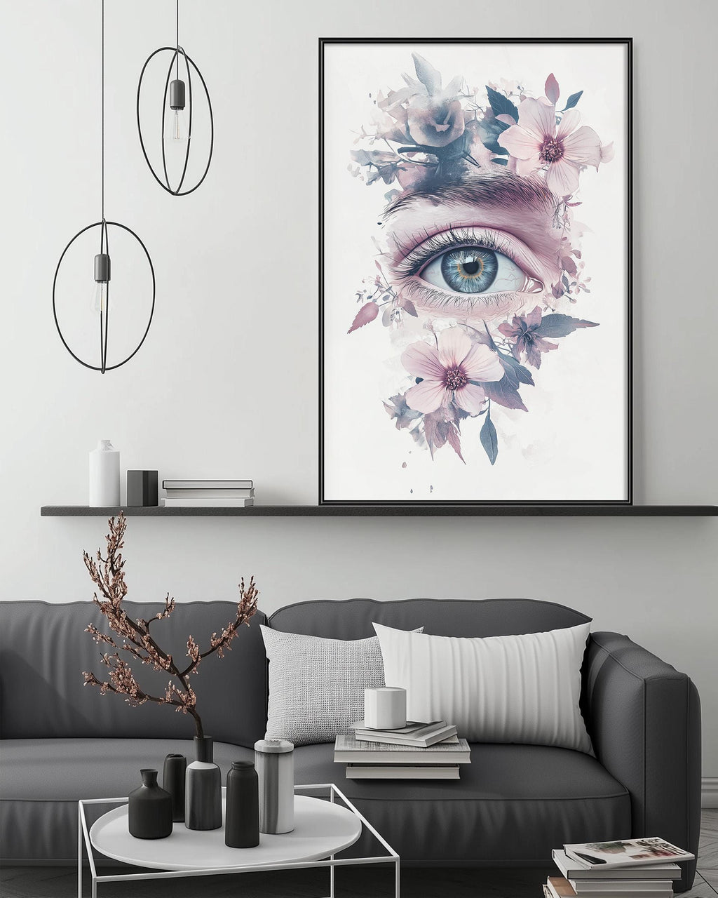 a large framed artwork depicting a close-up of an eye surrounded by a floral design, hanging above a gray couch in a living room setting.
