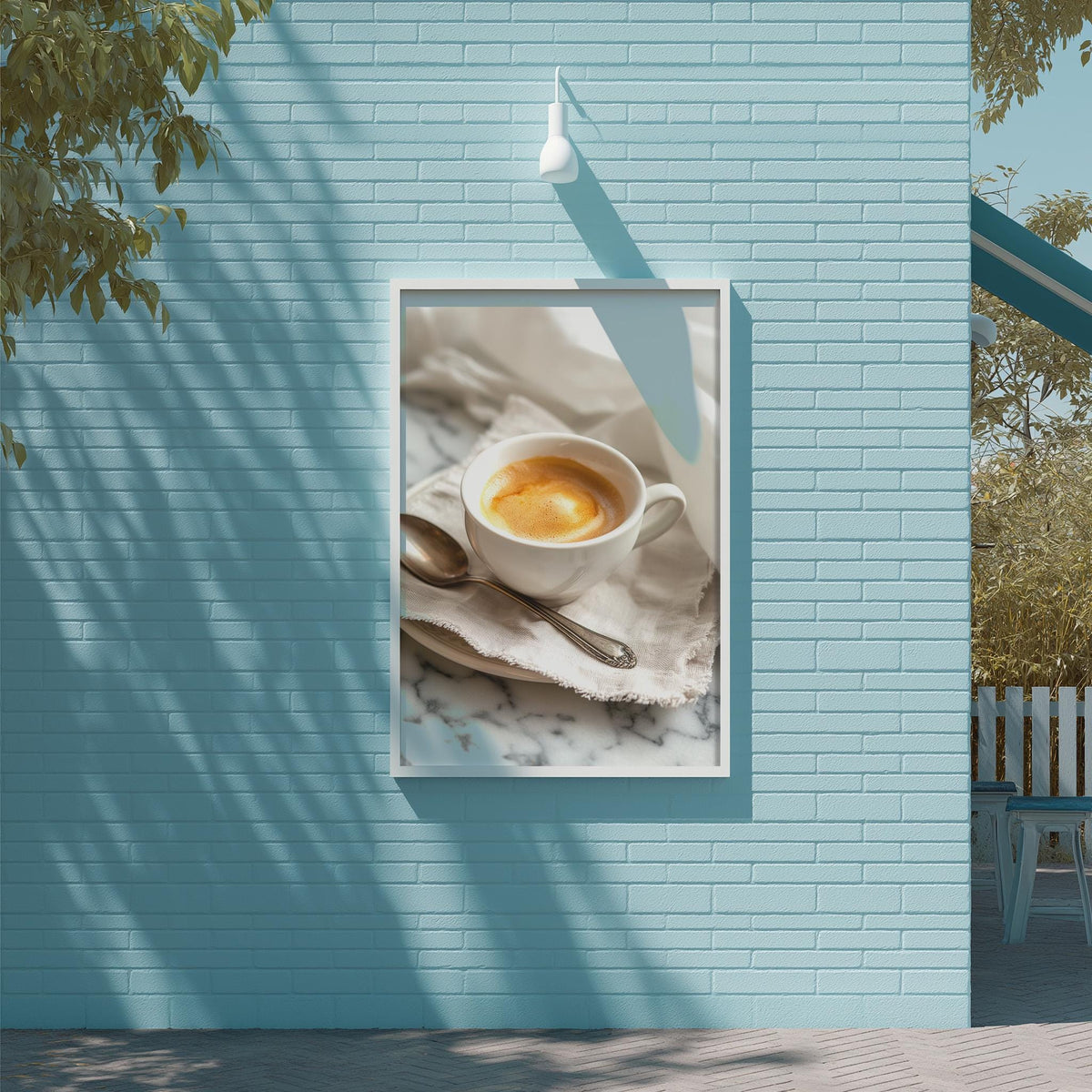 A framed image of a cup of coffee is displayed on a blue brick wall, with a white light fixture above it.