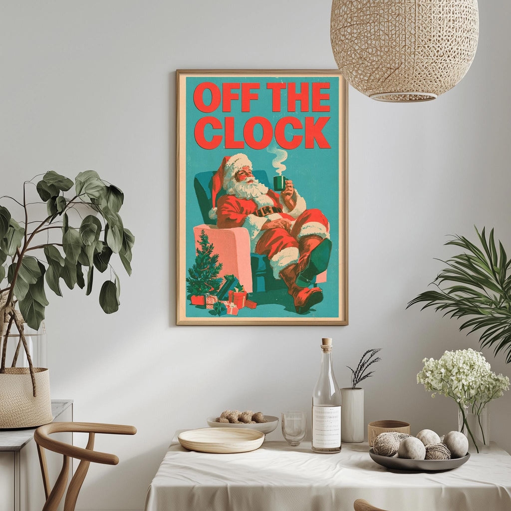 a framed poster of Santa Claus sitting in a chair, with the text "OFF THE CLOCK" written on it. The poster is hanging on a wall above a dining table with various items on it, including a bottle, a bowl, and a vase.