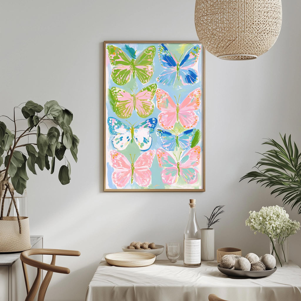 a dining table with a white tablecloth, a bowl of fruit, a bottle, and a vase with flowers. Above the table, there is a framed print of colorful butterflies on a blue background.