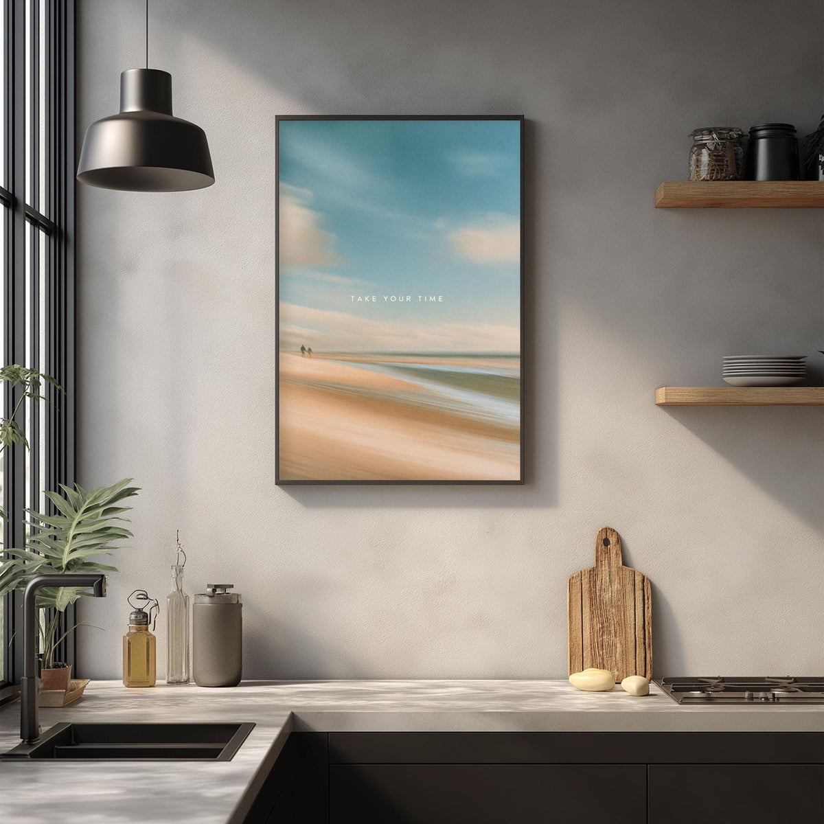 a kitchen counter with a framed picture of a beach scene hanging above it. The kitchen counter also has various kitchen items such as a cutting board, a knife, and a bottle.