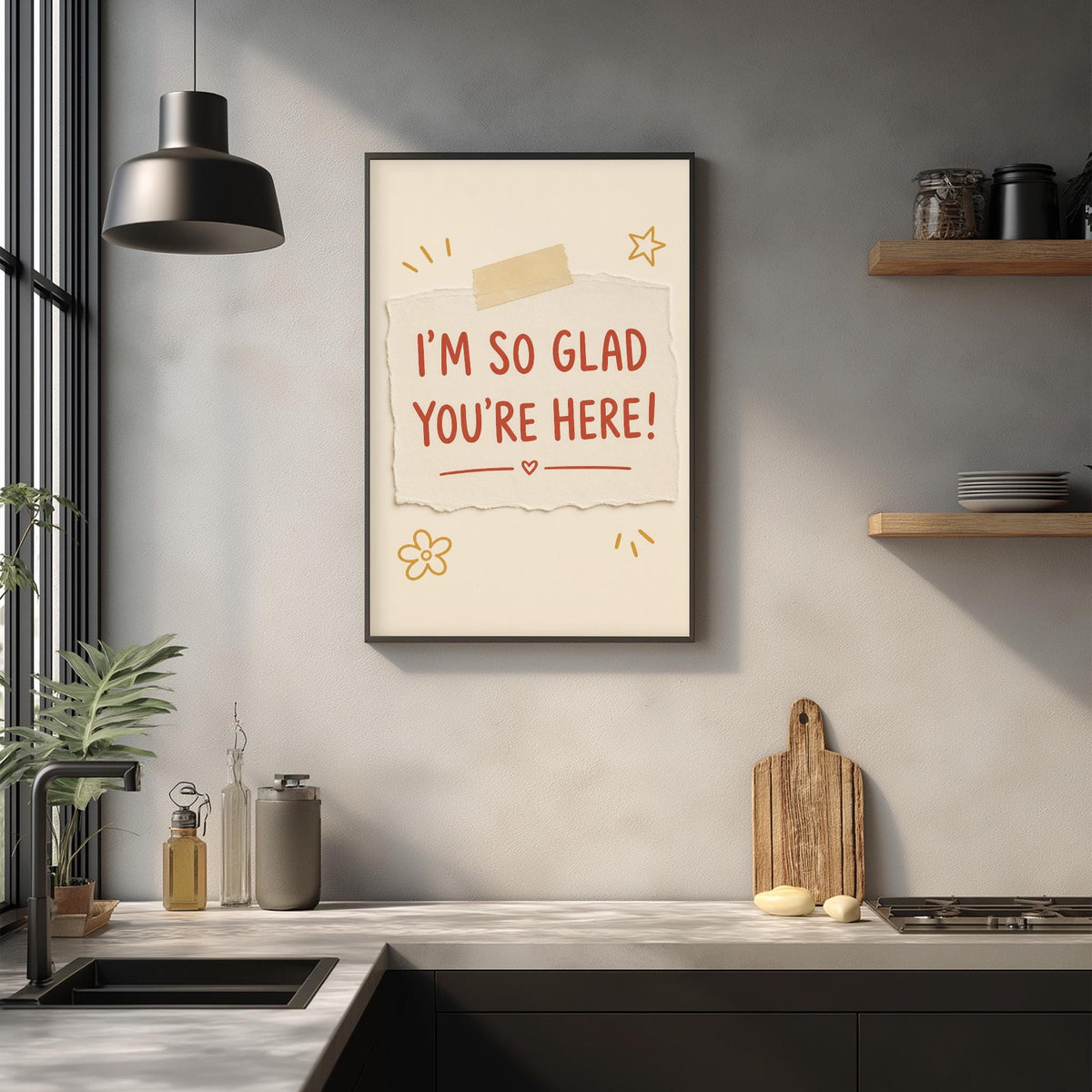 a kitchen counter with a framed poster hanging on the wall above it. The poster has a message that says "I'm so Glad You're Here!"