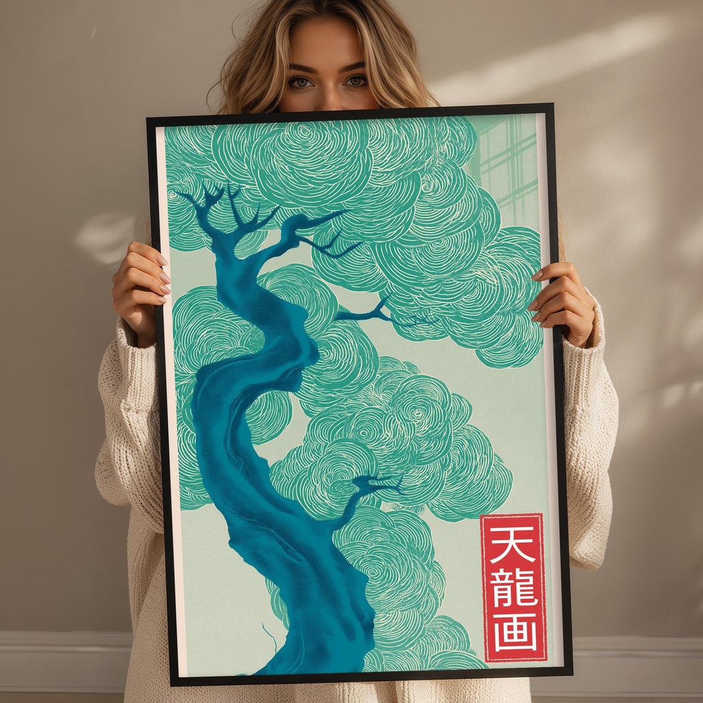 A woman is holding up a framed poster with a stylized tree design in shades of blue and green.