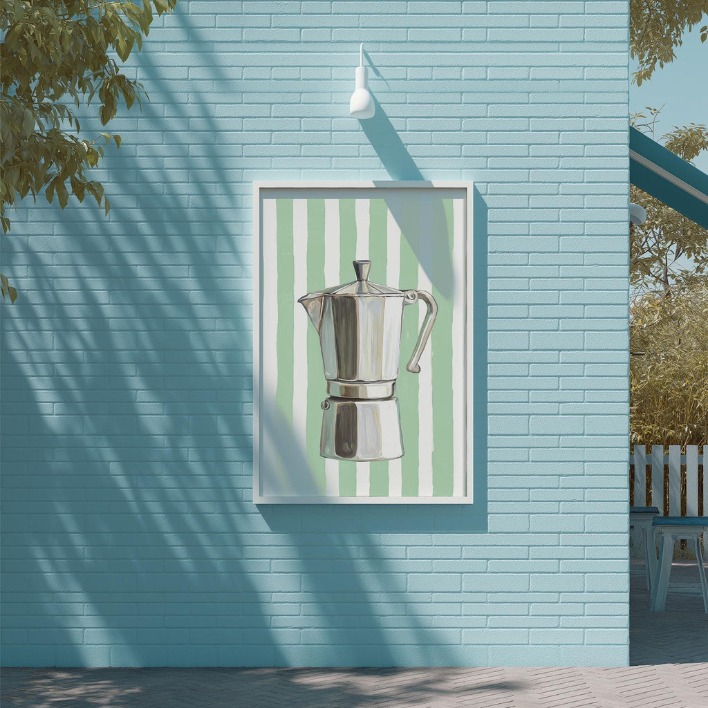 A framed image of a silver coffee maker is displayed on a blue brick wall, with a white light fixture above it.