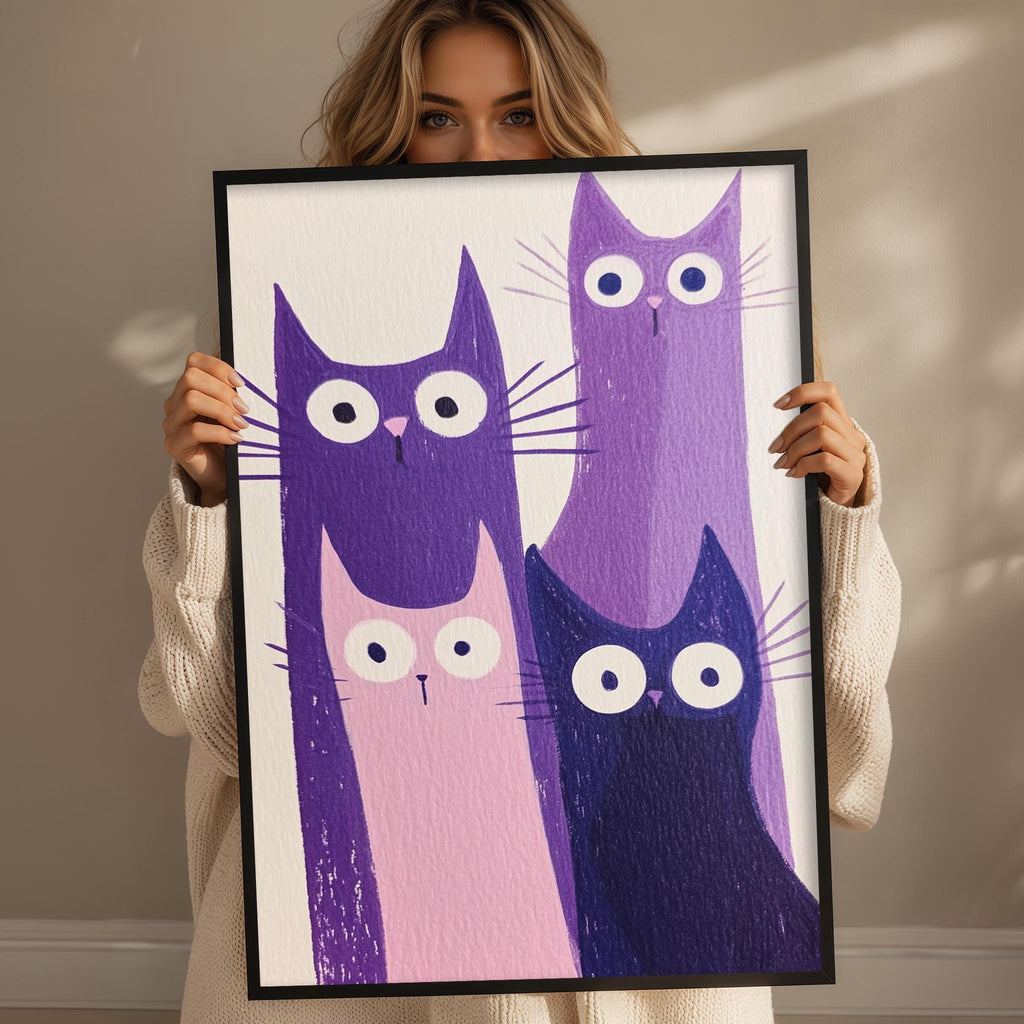 A woman is holding up a framed picture of four cats with large, expressive eyes.