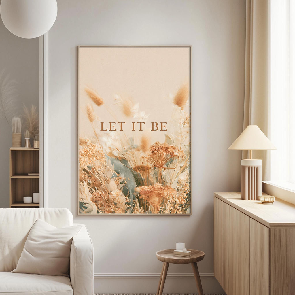 a living room with a large framed poster of flowers hanging on the wall. The poster has the text "LET IT BE" written on it. The room also includes a white couch, a small table, and a lamp.