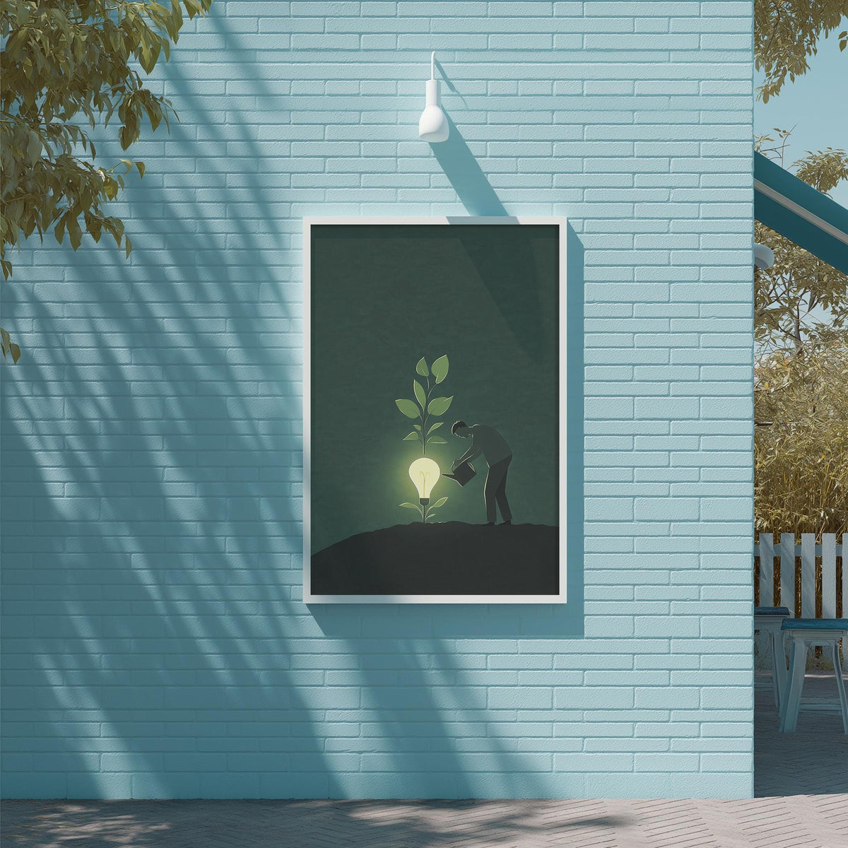 A framed illustration of a person watering a plant with a glowing light bulb above it, set against a blue brick wall.