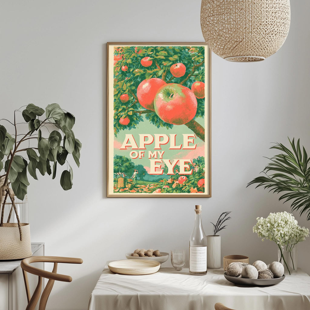 a framed vintage poster of an apple tree with the text "APPLE OF MY EYE" on it, hanging on a wall above a dining table with various items on it.
