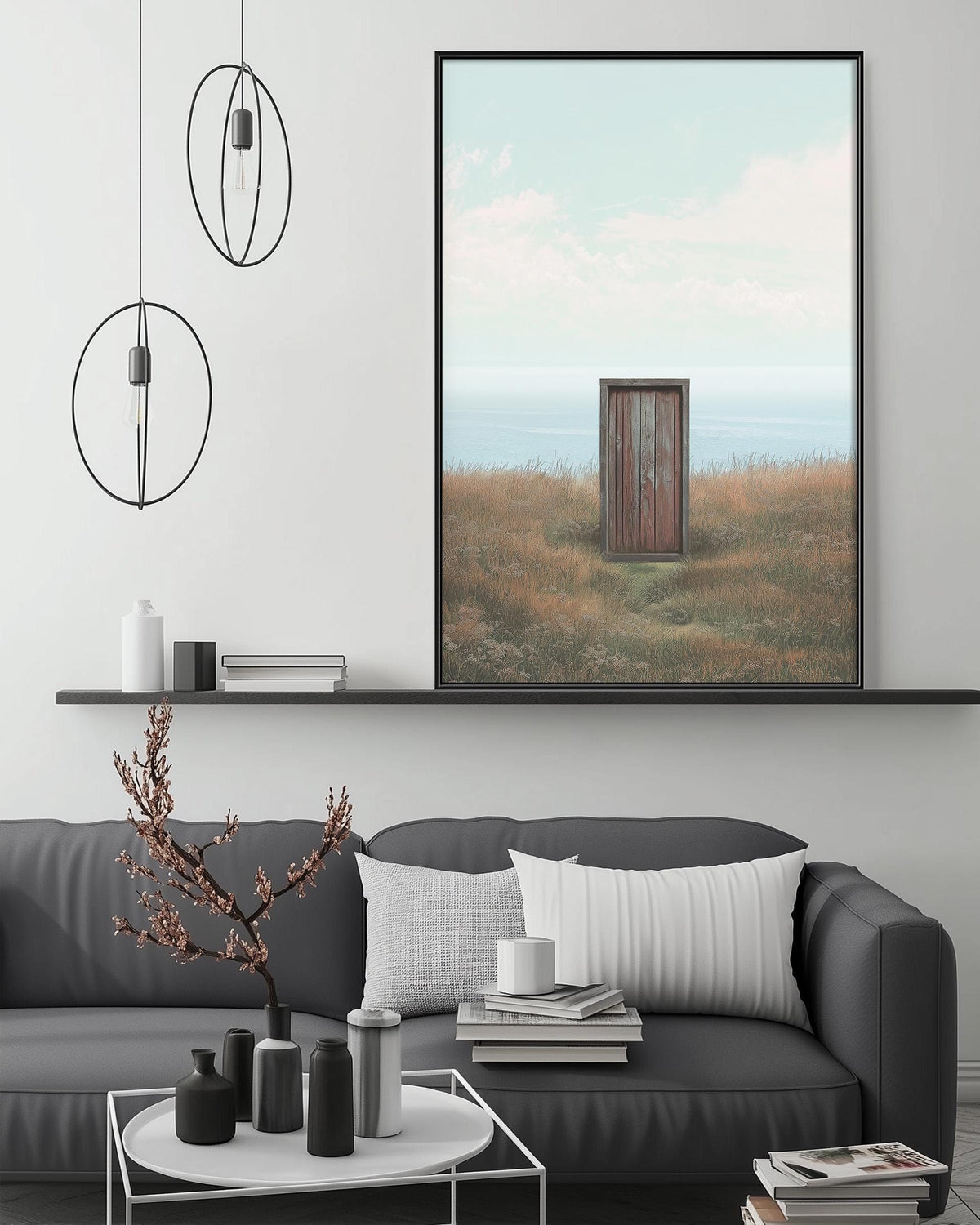 a living room with a gray sofa, a coffee table, and a large framed picture of a toilet in a field. The room has a minimalist and modern design, with a black pendant light hanging above the sofa and a shelf displaying decorative items.