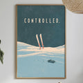 a framed poster of skiers on a snowy mountain, hanging on a wall above a dining table with various items on it.