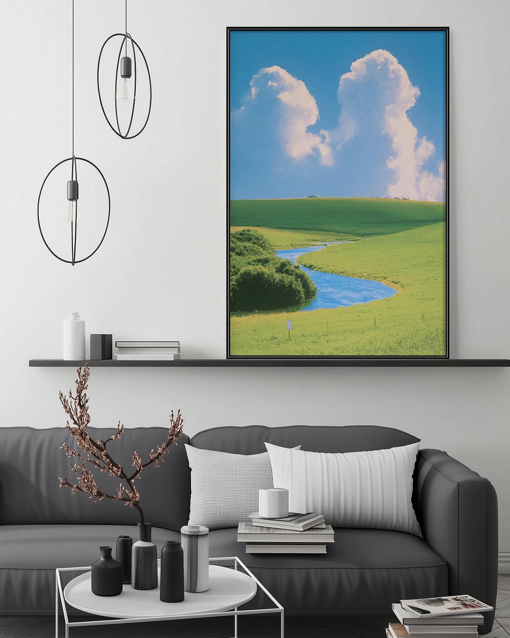 a living room with a gray sofa, a coffee table, and a large framed landscape painting depicting a serene countryside scene with a winding river and lush green fields.