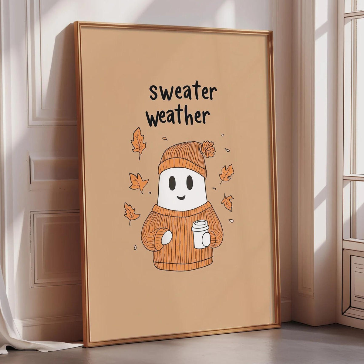 A framed illustration of a ghost wearing a sweater and holding a cup of coffee, with the text "Sweater weather" written above it.