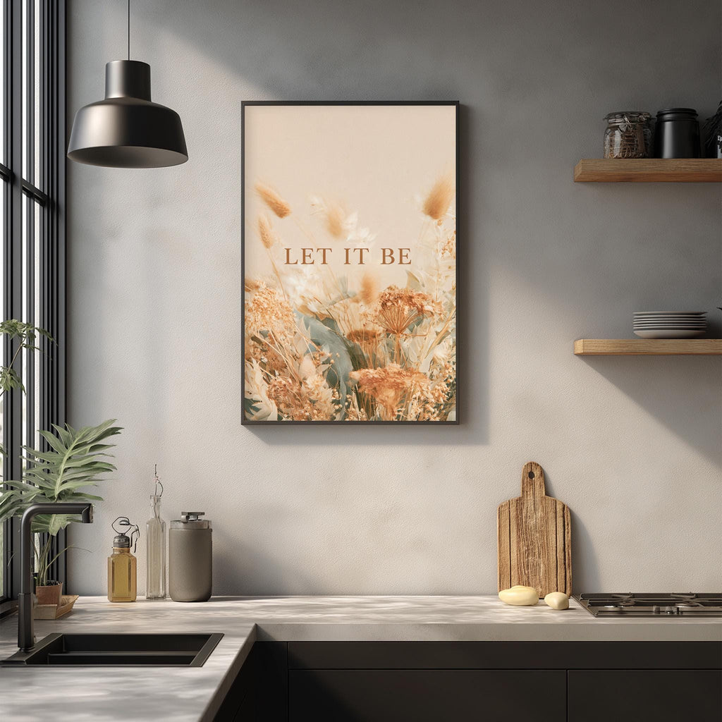 a kitchen counter with a framed poster of flowers hanging above it, a wooden cutting board, and various kitchen items such as a bottle and a jar.