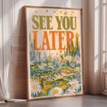 a framed poster with a large text that reads "See you later" and an illustration of a crocodile surrounded by flowers.