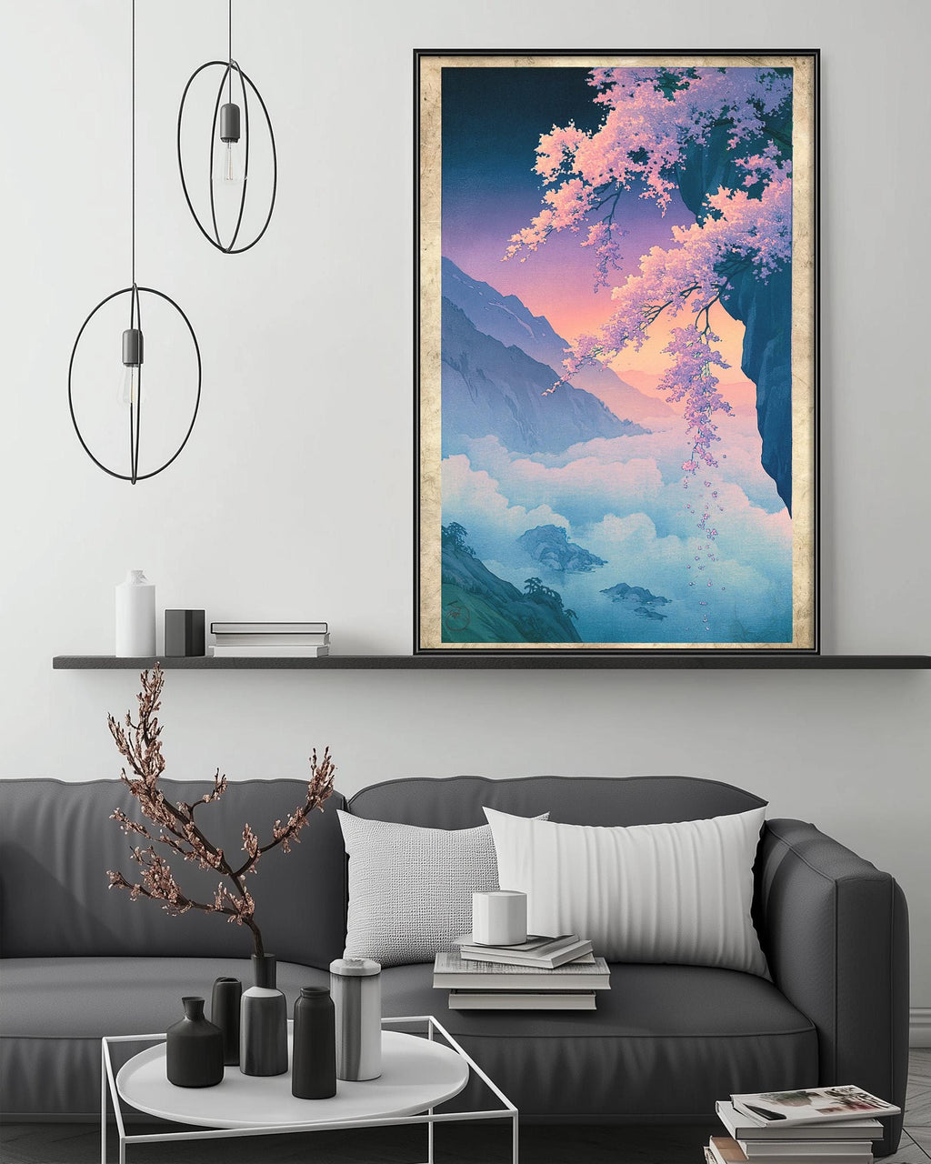 a large, colorful painting of a mountain landscape hanging on a wall above a gray couch with white pillows. The painting depicts a serene and picturesque scene of a mountain range with a clear sky and vibrant colors.