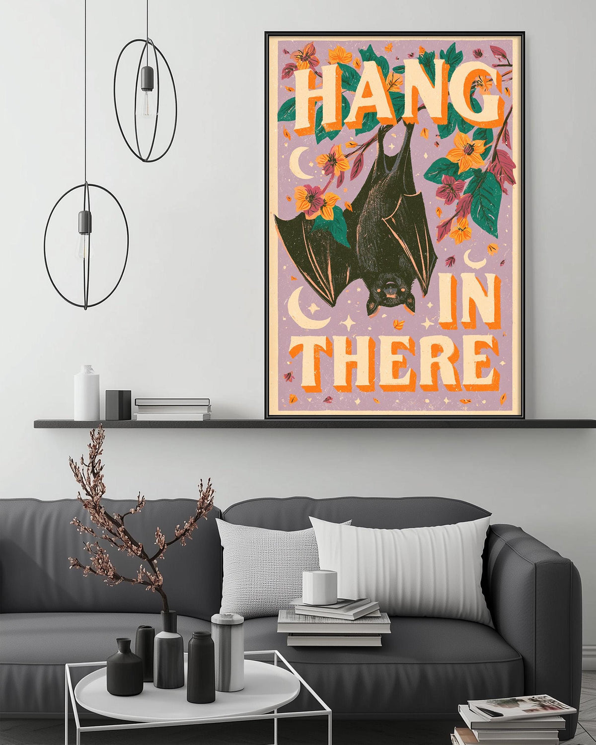 a living room with a gray couch, a coffee table, and a framed poster with a bat and the text "HANG IN THERE" on it.