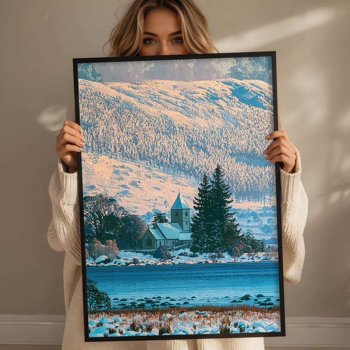 A woman holds up a framed picture of a snowy landscape with a church in the background.