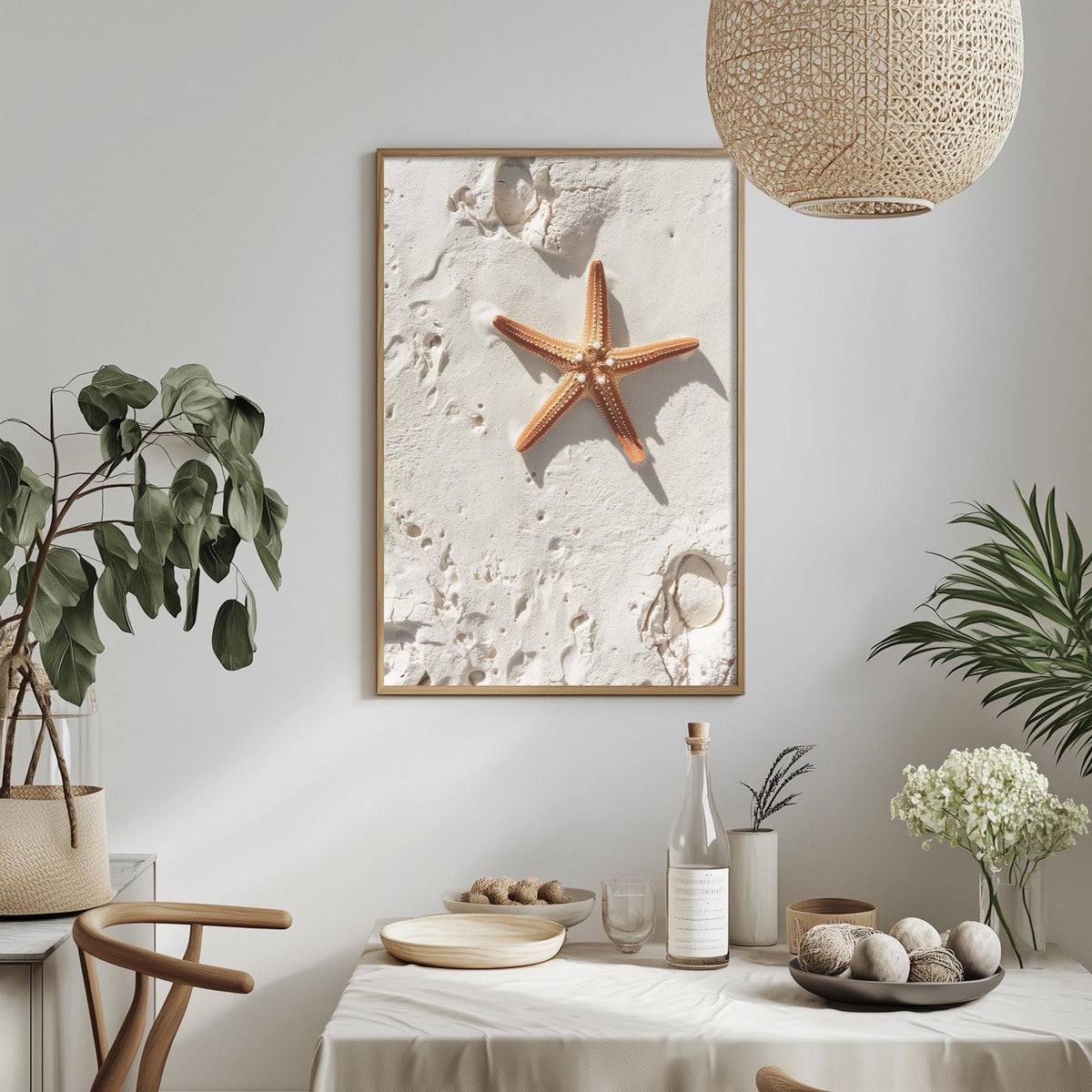 a serene beach scene with a framed photograph of a starfish on the wall, surrounded by potted plants and a dining table with various items on it.