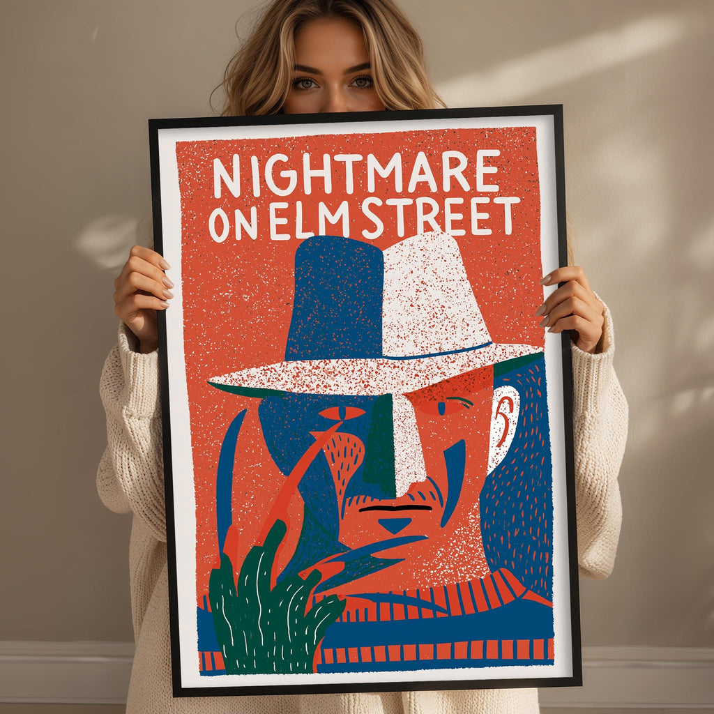 A woman is holding up a framed poster of a man's face, which appears to be a depiction of Freddy Krueger from the horror film " Freddy Krueger on Elm Street".