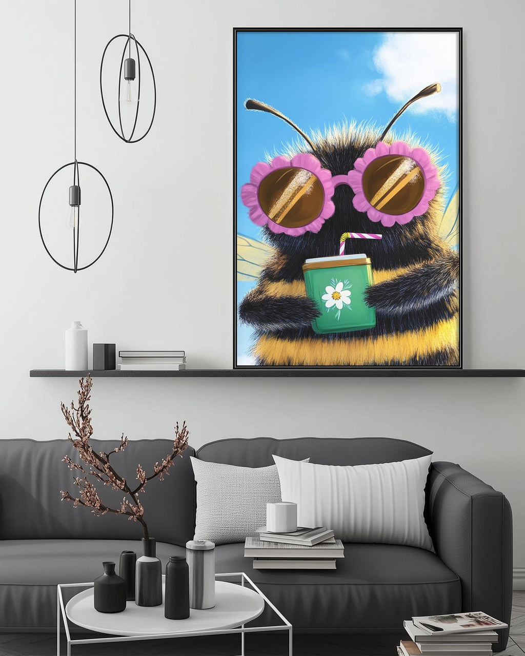 a large, colorful painting of a bee wearing sunglasses and holding a drink, hanging on a wall above a gray couch in a living room setting.