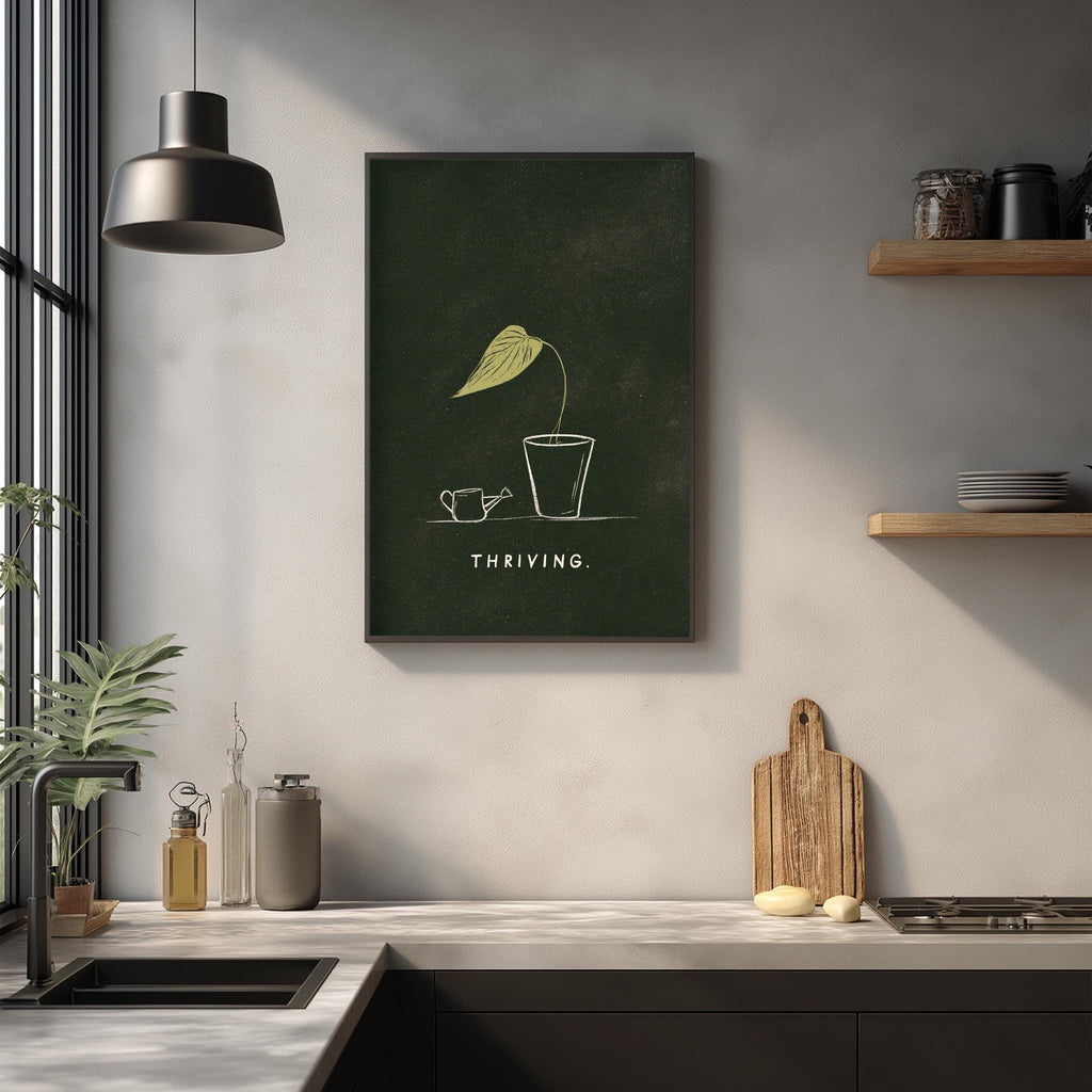 a kitchen counter with various kitchen items, including a cutting board, a plant, and a framed poster with the word "THRIVING" on it.