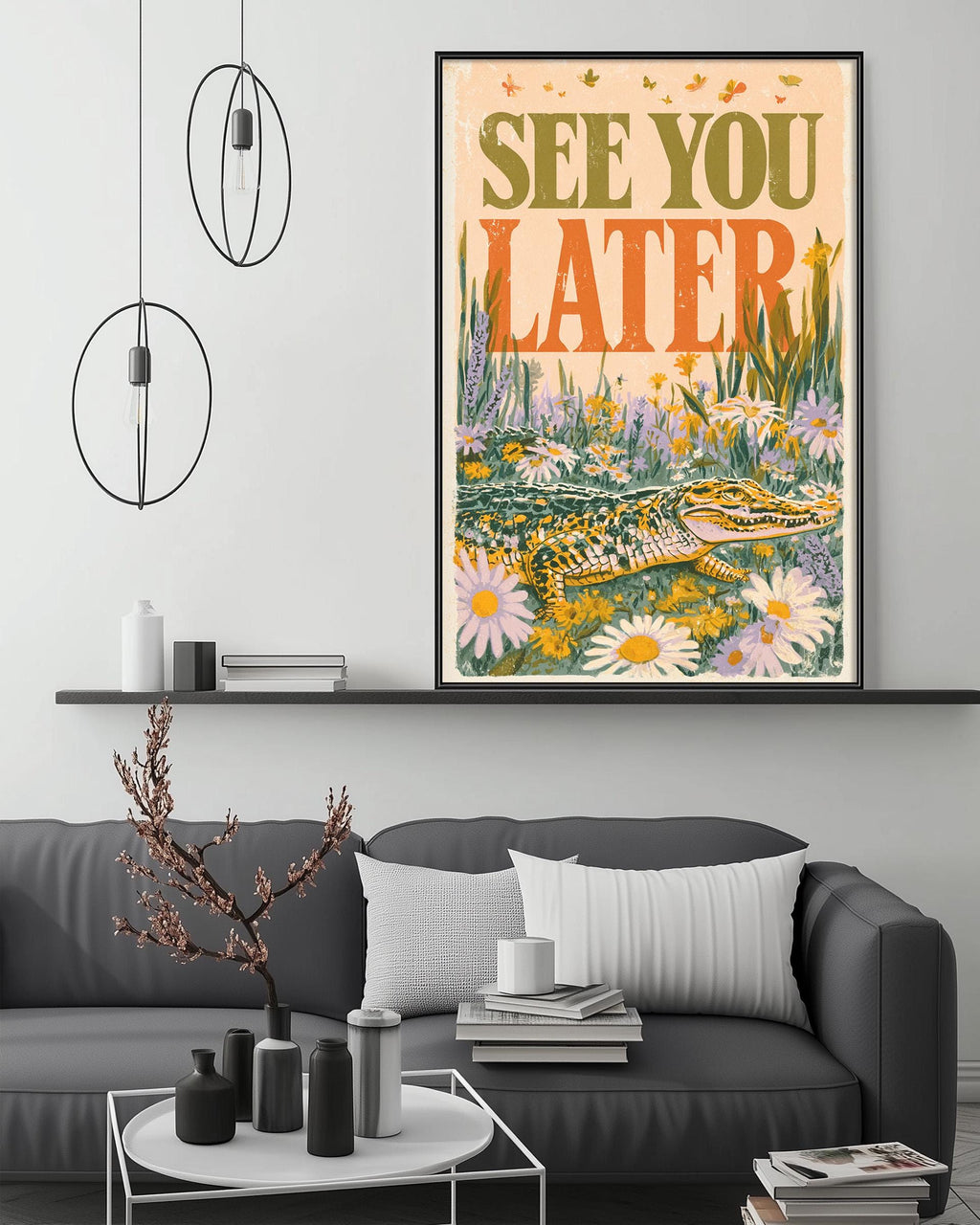 a large framed poster with the text "See you later" on it, hanging on a wall above a gray couch with a coffee table in front of it.