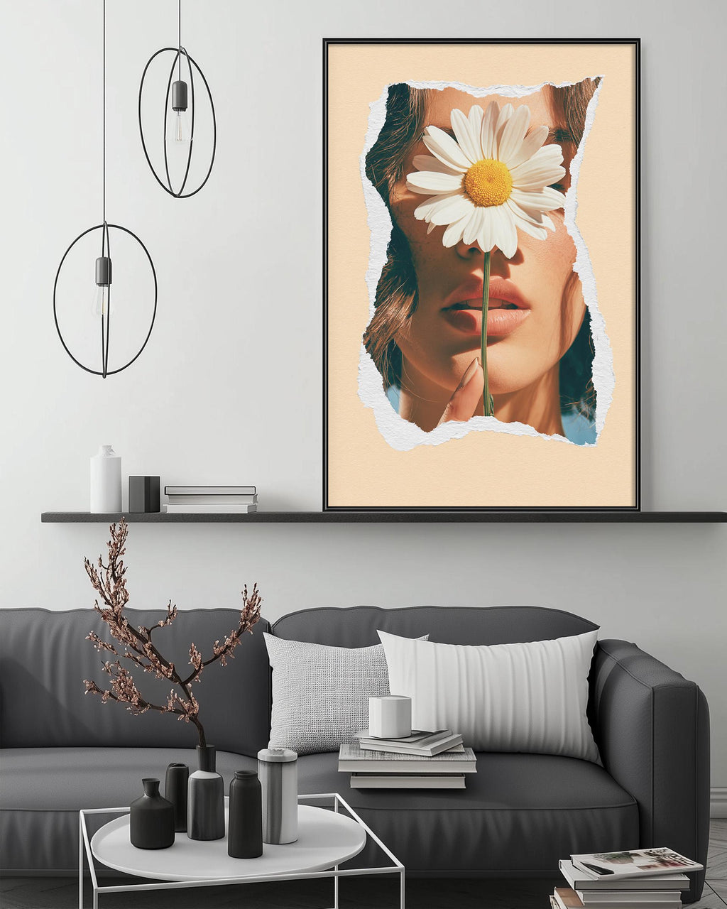 a modern living room with a gray sofa, a coffee table, and a large framed print of a woman's face with a flower in her mouth. The room has a minimalist and stylish design, with pendant lights hanging above the sofa and a shelf displaying decorative items.