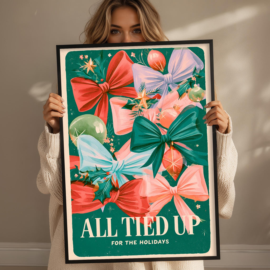 A woman is holding up a framed poster with a festive design featuring colorful bows and Christmas ornaments.