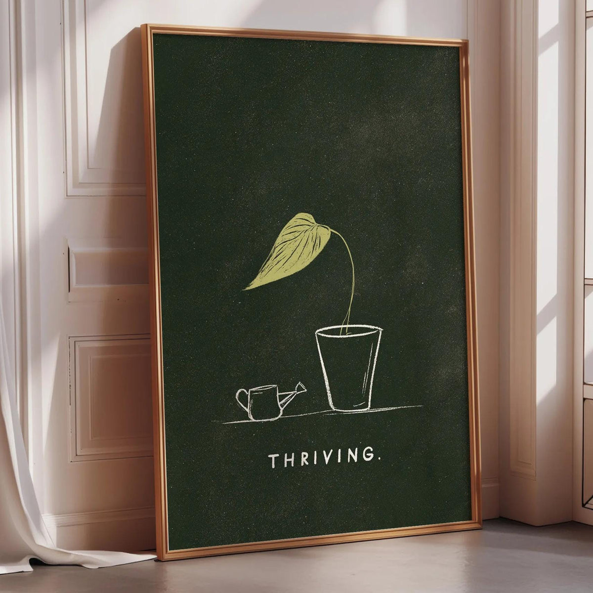 A framed poster with a green background and a yellow leaf illustration, along with the text "THRIVING" below the leaf.