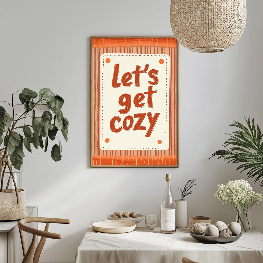 a cozy atmosphere with a framed text that reads "Let's get cozy" hanging on a wall above a dining table. The table is set with various items, including a bottle, a bowl, and a vase with flowers. The room is decorated with potted plants and a woven light fixture, creating a warm and inviting ambiance.